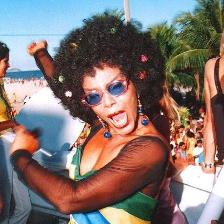 Person with colorful hair and sunglasses at a beach party