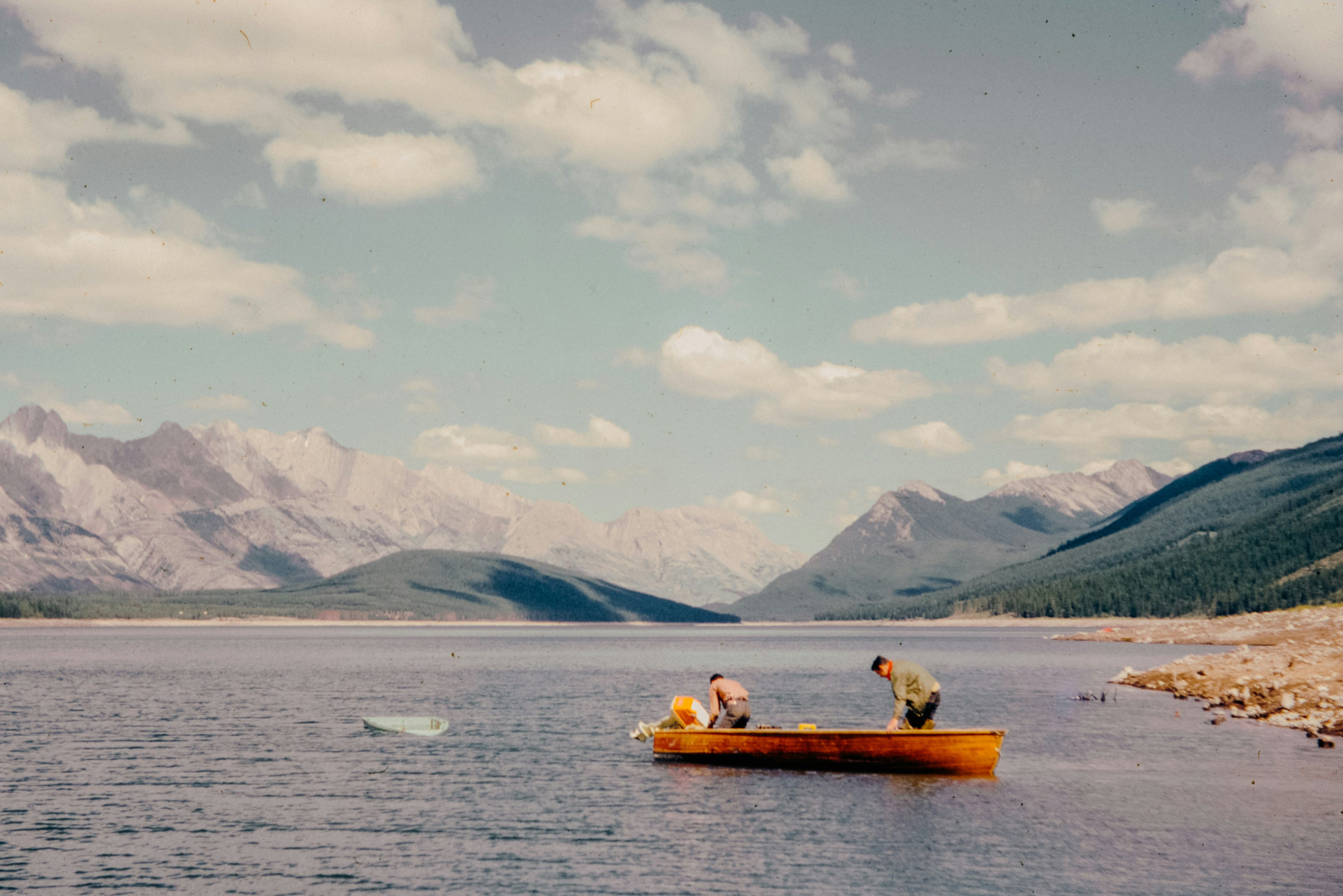 men in a boat next to moutains